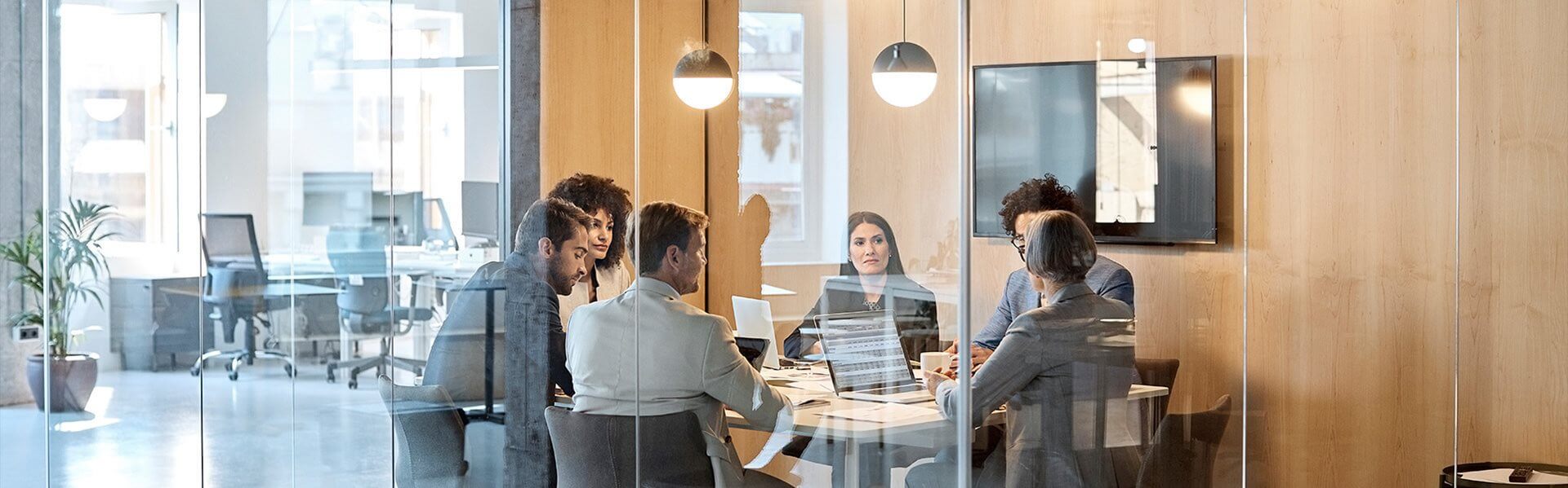 A diverse group of professionals have a table discussion in a corporate meeting room. 